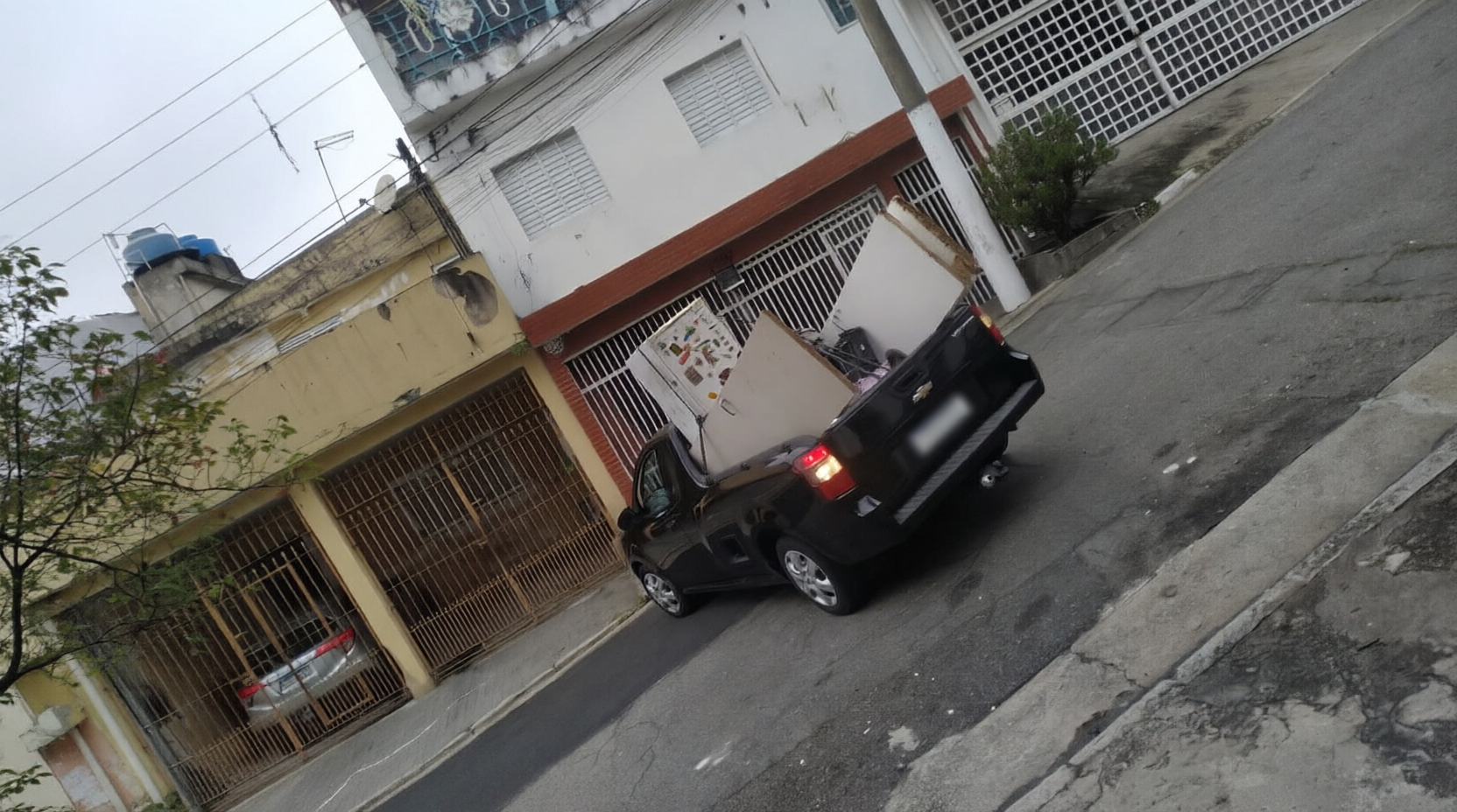 Caminhonete carregada com móveis em rua inclinada